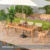 An outdoor dining set with a wooden table and chairs under a large umbrella, set on a patio next to a garden with flowers and plants. Anteprima dell’immagine prodotto