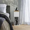 A bedside table next to a bed with a phone charging on it. Náhled obrázku produktu