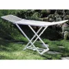 A white foldable clothes drying rack is set up on a grassy lawn with rocks and plants in the background. Produktbild-Vorschau
