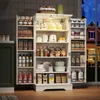 A well-lit kitchen pantry cabinet filled with various food items and kitchenware, with a window showing a house at dusk in the background. Voir les images du produit