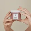 Hands holding a jar of skincare product. Produktbild-Vorschau