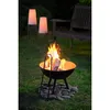 A fire pit with flames and tongs is set up on a lawn at dusk, with two modern lamps and a wooden bench in the background. Produktbild-Vorschau