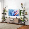 A living room scene with a TV stand, a large television, and two multi-tiered plant stands filled with various plants. Podgląd zdjęcia produktu