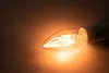 A close-up shot of a lit LED filament candle light bulb. Produktbild-Vorschau