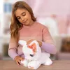 A young girl is holding a white plush toy bunny with a pink bow. Anteprima dell’immagine prodotto