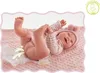 A baby doll lying on a pink blanket with a diaper that appears to be leaking. Anteprima dell’immagine prodotto
