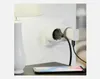 A white wall outlet with a white dual adapter plugged in, charging a phone. Produktbild-Vorschau