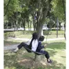 Two people sitting on a net swing attached to a tree in a park. Anteprima dell’immagine prodotto
