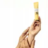A hand holding a tube of Lierac Sunissime Fluid SPF50+ against a white background. Produktbild-Vorschau