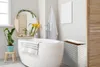A modern bathroom with a freestanding bathtub, a round mirror decorated with greenery, and a plant. Podgląd zdjęcia produktu