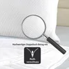 A close-up view of a white pillow with a magnifying glass highlighting the fabric texture, and icons indicating features. Produktbild-Vorschau