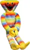 A rainbow-colored plush toy with a wide, toothy grin is sitting with its legs extended. Produktbild-Vorschau