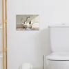 A framed picture of penguins in a bathtub hangs on a wall next to a toilet. Produktbild-Vorschau