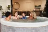 A family enjoying a hot tub indoors, with a Christmas tree in the background. Náhled obrázku produktu