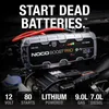 A car battery jump starter is shown connected to a car battery in an engine bay. Produktbild-Vorschau
