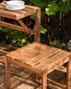 A close-up view of a wooden garden bench with a bowl on the top shelf, set outdoors on a wooden deck with greenery in the background. Produktbild-Vorschau