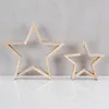 Two wooden star decorations are displayed on a white surface against a gray concrete wall. Produktbild-Vorschau
