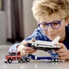 A young boy wearing glasses is playing with a Lego space shuttle transporter. Voir les images du produit