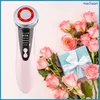 A pink facial massage device is placed next to a bouquet of pink roses and a light blue gift box. Náhľad obrázku produktu