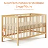 A wooden baby crib with a beige mattress, shown from a low angle. Produktbild-Vorschau