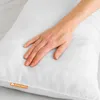 A hand is pressing down on a white pillow. Produktbild-Vorschau