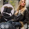 A woman is pushing a stroller outdoors, wearing stroller gloves. Produktbild-Vorschau
