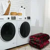 A laundry room scene with two washing machines, laundry supplies, and a folded plaid blanket. Produktbild-Vorschau
