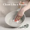 A hand is cleaning a light gray frying pan with a white cloth. Náhled obrázku produktu