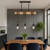 A dining room with a wooden table and chairs, illuminated by a pendant light fixture. Produktbild-Vorschau