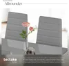 A close-up of two gray dining chairs with a vase of flowers and a glass on a table. Produktbild-Vorschau