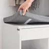 A hand is shown adjusting a gray cushion on top of a white cabinet. Anteprima dell’immagine prodotto