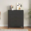 A dark gray metal dresser with four drawers is shown in a room with a light gray wall and a wooden floor. Produktbild-Vorschau
