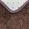 Close-up of the corner of a brown shaggy rug, showing the underside with a pattern of dots and small flowers, and a purple and white stitched border. Náhled obrázku produktu