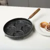 A non-stick frying pan with a granite coating and a wooden handle is shown on a white countertop. A plate with pancakes is visible to the right. Produktbild-Vorschau