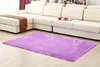 A purple shaggy rug is placed on a wooden floor in front of a large white sectional sofa. Náhled obrázku produktu