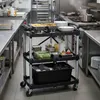 A commercial kitchen with a three-tiered serving cart filled with food and utensils. Produktbild-Vorschau