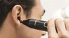 A person is using a Philips nose trimmer to trim ear hair. Podgląd zdjęcia produktu
