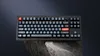 A black mechanical keyboard with gray keys is displayed on a rock formation against a dark background. Náhľad obrázku produktu