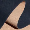 A close-up view of a dark blue yoga mat with a cork backing, partially unrolled. Produktbild-Vorschau