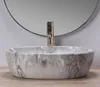 A marble-effect basin with a gold faucet is shown in a bathroom setting. Náhled obrázku produktu