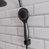 Schwarze Handbrause vor Duschrückwand mit weißer Fliesenoptik Produktbild-Vorschau
