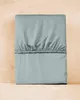 A folded mint-colored fitted sheet is placed on a wooden surface. Produktbild-Vorschau
