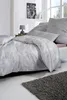 A neatly made bed with a duvet and pillows, featuring a subtle patterned fabric. Produktbild-Vorschau