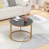 A round coffee table with a marble top and gold legs is placed on a rug in a living room setting, next to a sofa. Produktbild-Vorschau