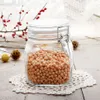 A glass jar filled with small orange beans, placed on a white doily on a wooden surface. Decorative branches with red berries are in the background. Produktbild-Vorschau