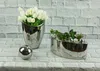 Three silver decorative items on a white brick background. Podgląd zdjęcia produktu