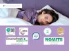 A woman is lying in bed, smiling at the camera. Below the image are several certification logos and product branding. Produktbild-Vorschau