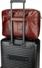 A brown leather briefcase is placed on top of a black rolling suitcase. Produktbild-Vorschau