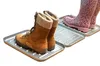 Two pairs of boots are placed on two separate shoe trays. The boots in the foreground are brown lace-up boots, and the boots in the background are pink leopard-print rain boots. Produktbild-Vorschau