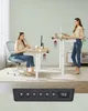 Two women using standing desks in an office setting. A control panel for the desk is shown in the foreground. Produktbild-Vorschau